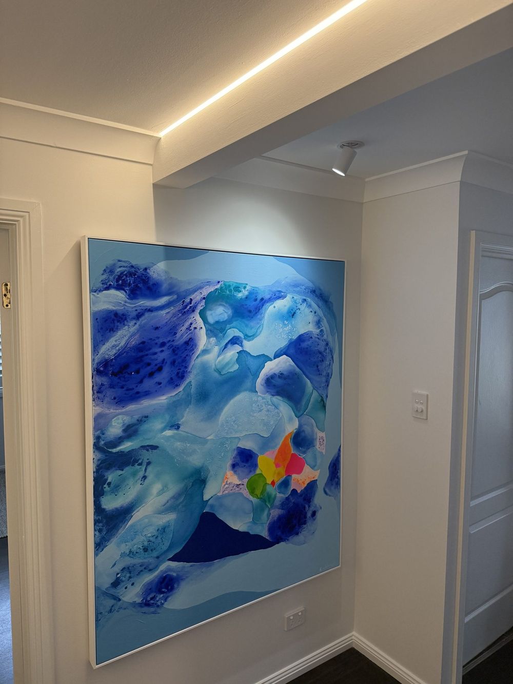 Hallway lighting washing an artwork in a finished home