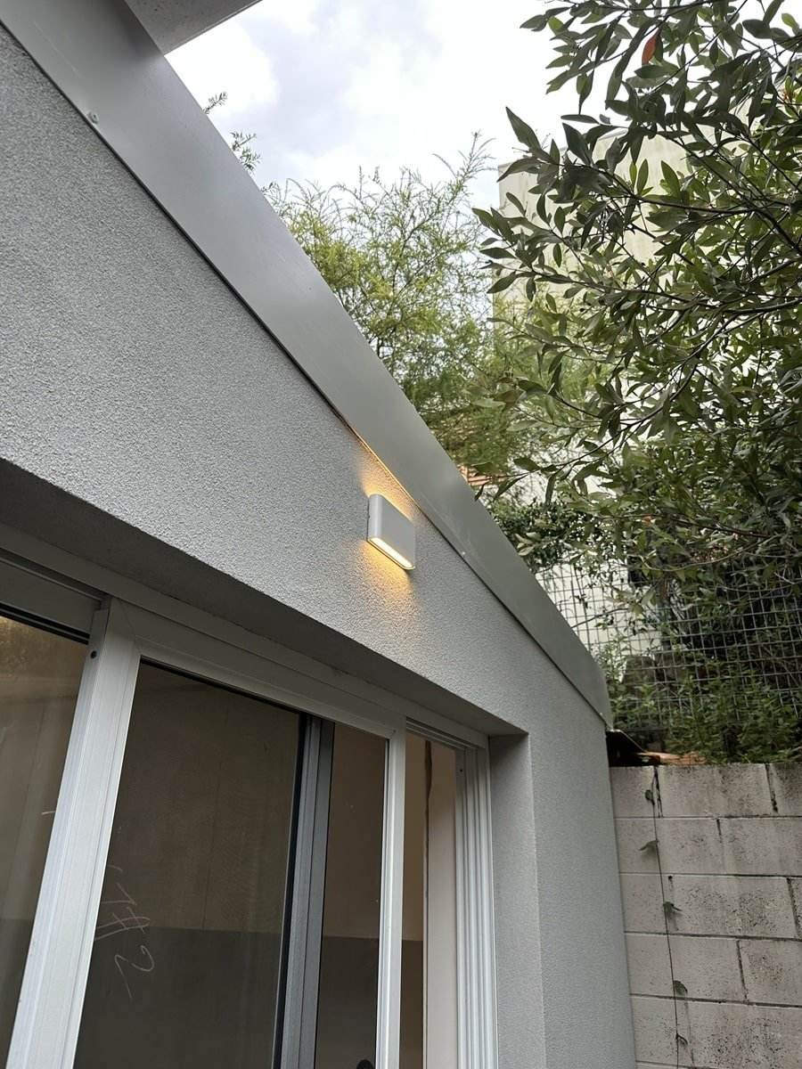 Recessed exterior wall light on a rendered home