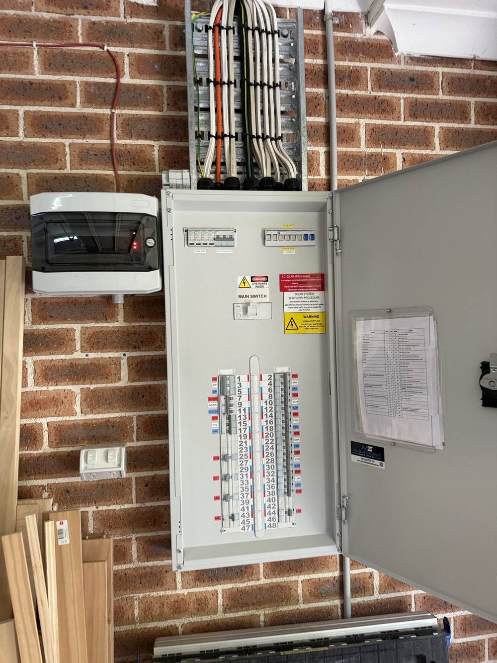 Switchboard mounted on a brick wall with the cover off
